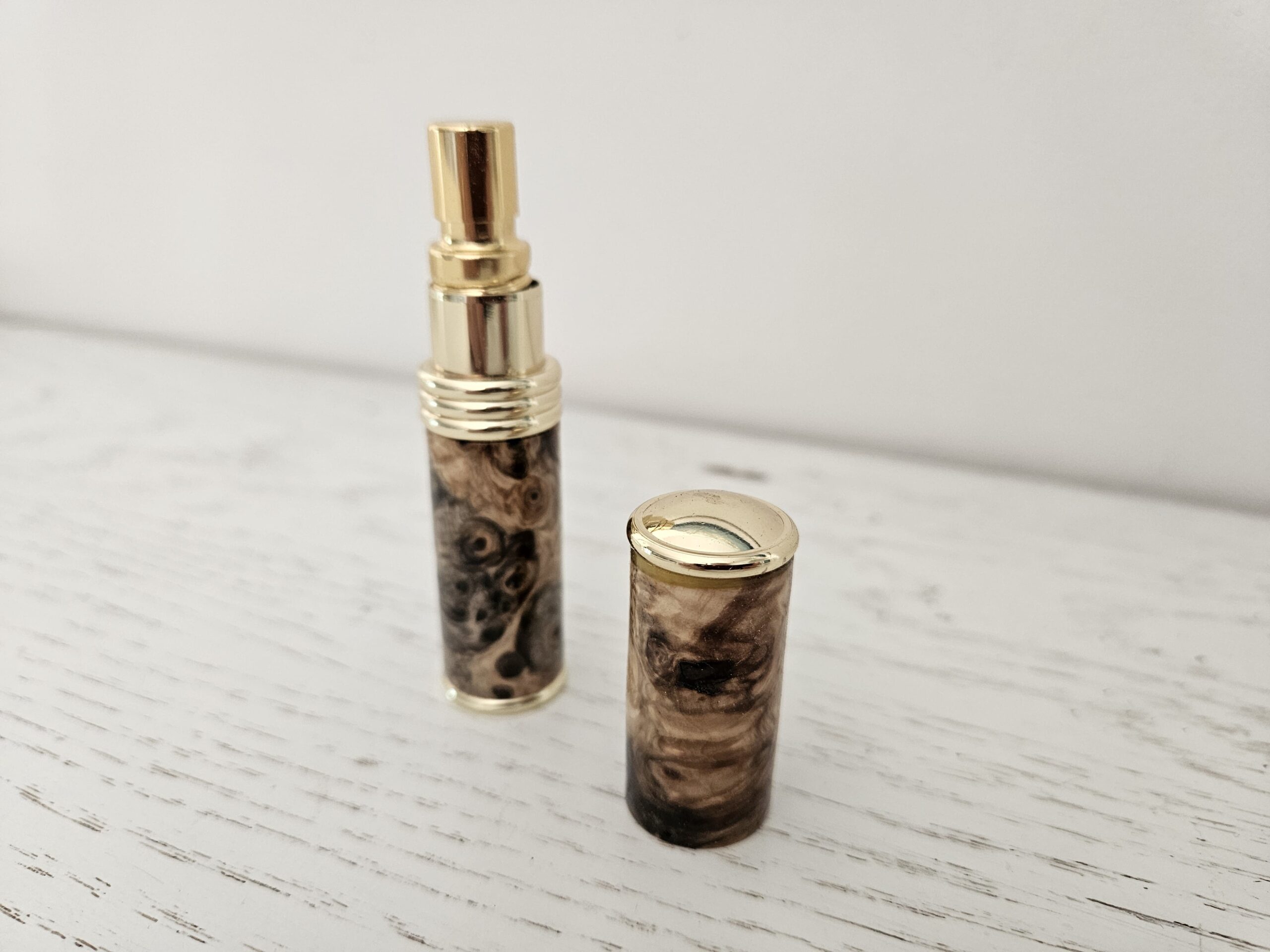 Atomiseur de parfum artisanal en loupe de marronnier, avec finitions dorées. Élégant, unique et pratique pour emporter votre fragrance partout avec style.